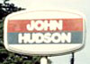 John Hudson logo with red and grey bands and white text